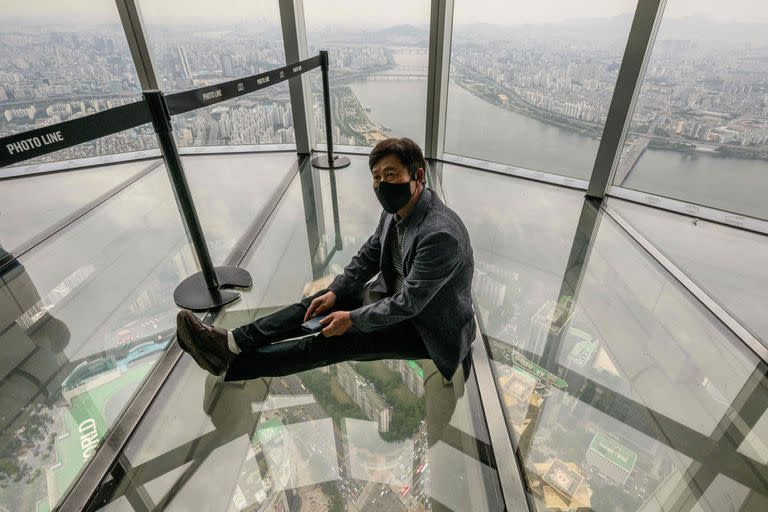 Un hombre sobre el piso de vidrio del rascacielos Lotte World Tower de 123 pisos.