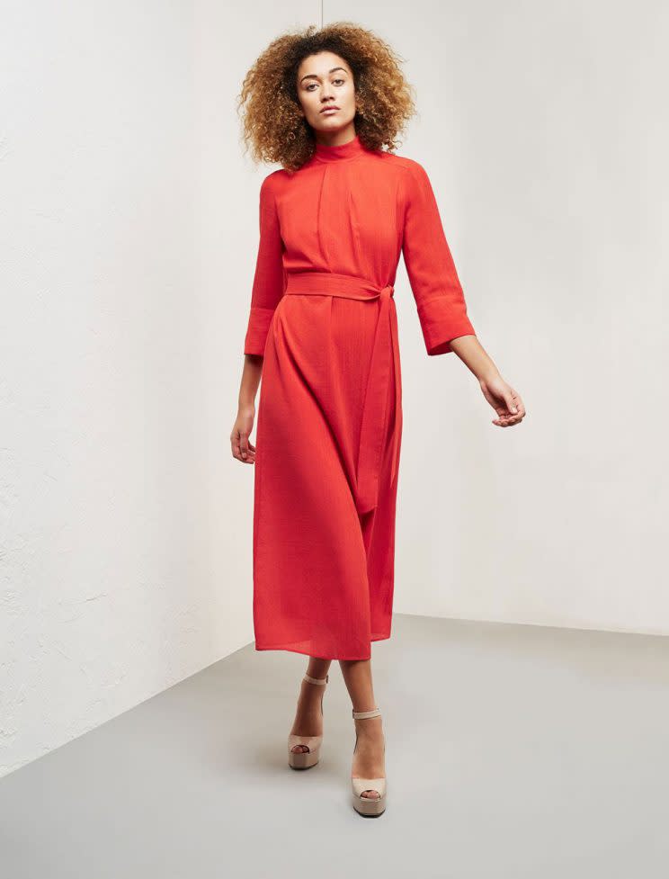 A model wears a poppy red high neck dress.