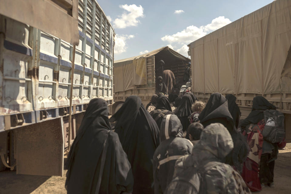 In this Wednesday, March 6, 2019, photo, women and children board a truck at a reception area for people evacuated from the last shred of territory held by Islamic State militants, outside Baghouz, Syria. (AP Photo/Gabriel Chaim)