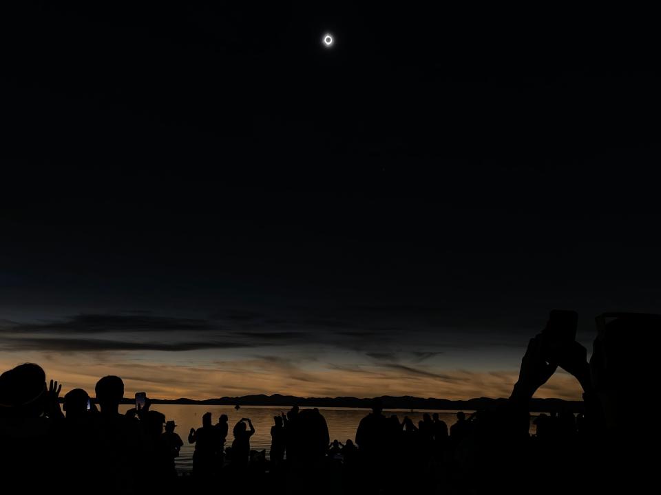 Crowds gathered at Perkins Pier stood up when the total solar eclipse occurred Monday, April 8, 2024. The sky darkened and the sun became a ring behind the moon.
