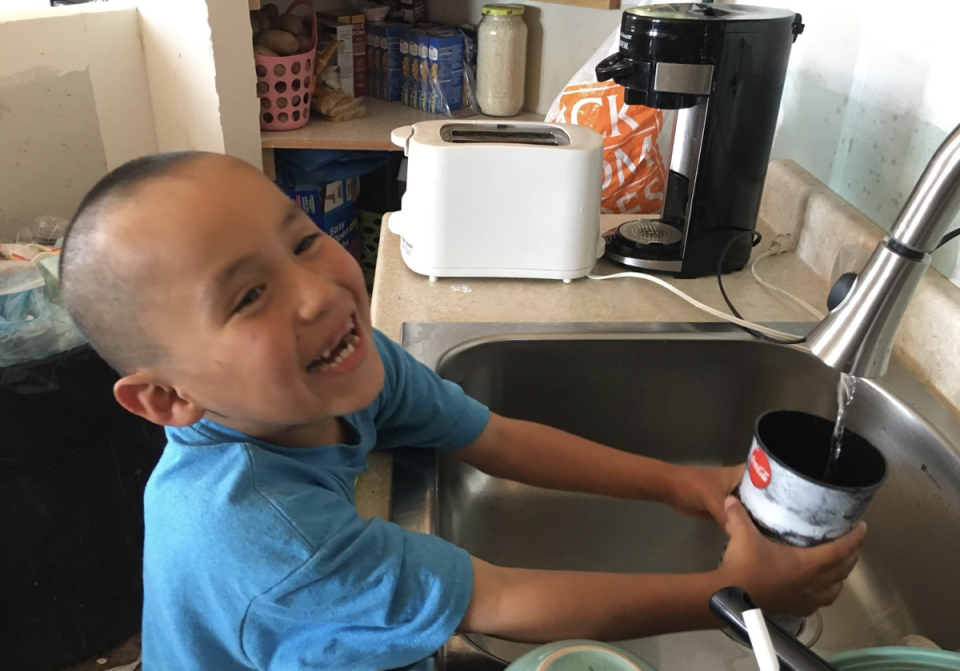 A young boy gets a glass of water after having running water installed by the Navajo Water Project (DigDeep)