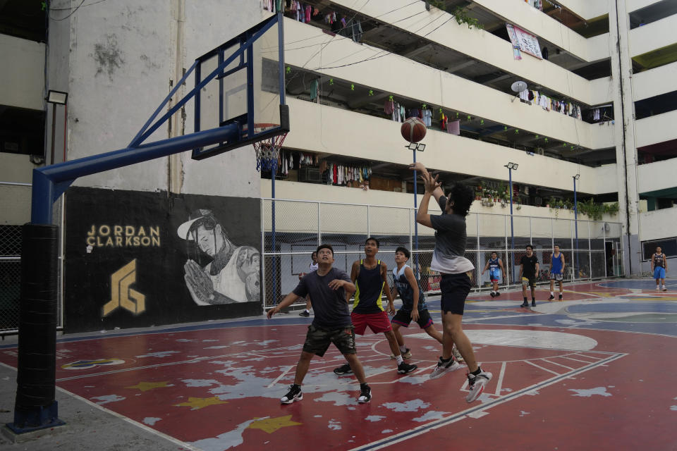 People play basketball in front of a wall painted with Jordan Clarkson, a Filipino-American NBA player for the Utah Jazz, on a FIBA Basketball World Cup themed court Thursday, Aug. 17, 2023, in Taguig city Philippines. Basketball's World Cup starts on Friday, spread out over three nations — the Philippines, Japan and Indonesia. It'll be centered in Manila. Fans have been waiting for years for this chance at seeing some of the game's biggest names competing in their city. (AP Photo/Aaron Favila)