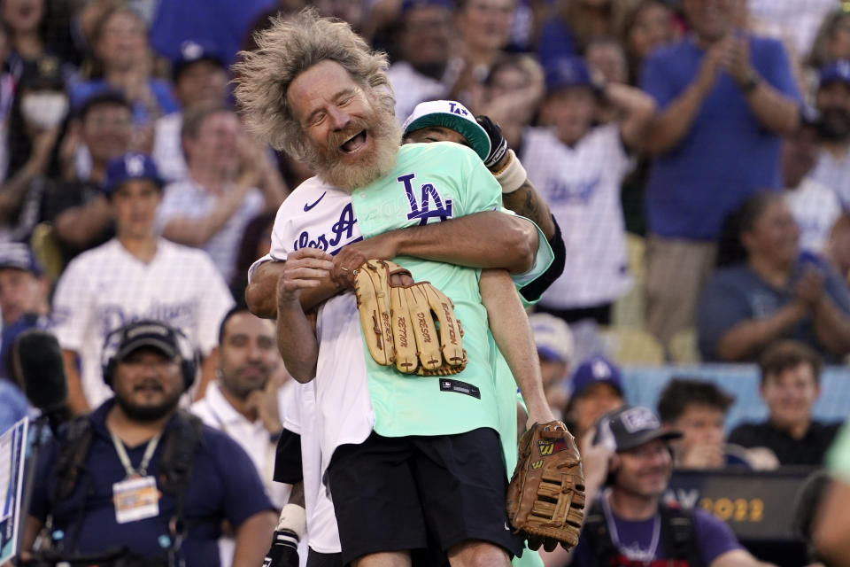 Actor Bryan Cranston is lifted by former Los Angeles Dodgers player Andre Ethier during the MLB All Star Celebrity Softball game, Saturday, July 16, 2022, in Los Angeles. (AP Photo/Mark J. Terrill)