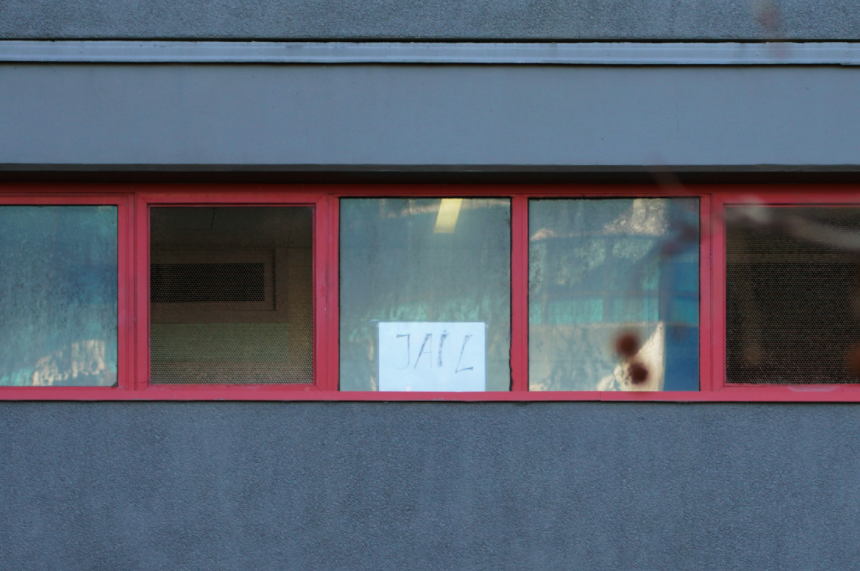 A resident places a 'jail' sign on their window as those inside are kept under police guard. (Reuters)