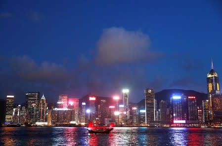 A junk boat passes the skyline as seen from the Tsim Sha Tsui waterfront in Hong Kong