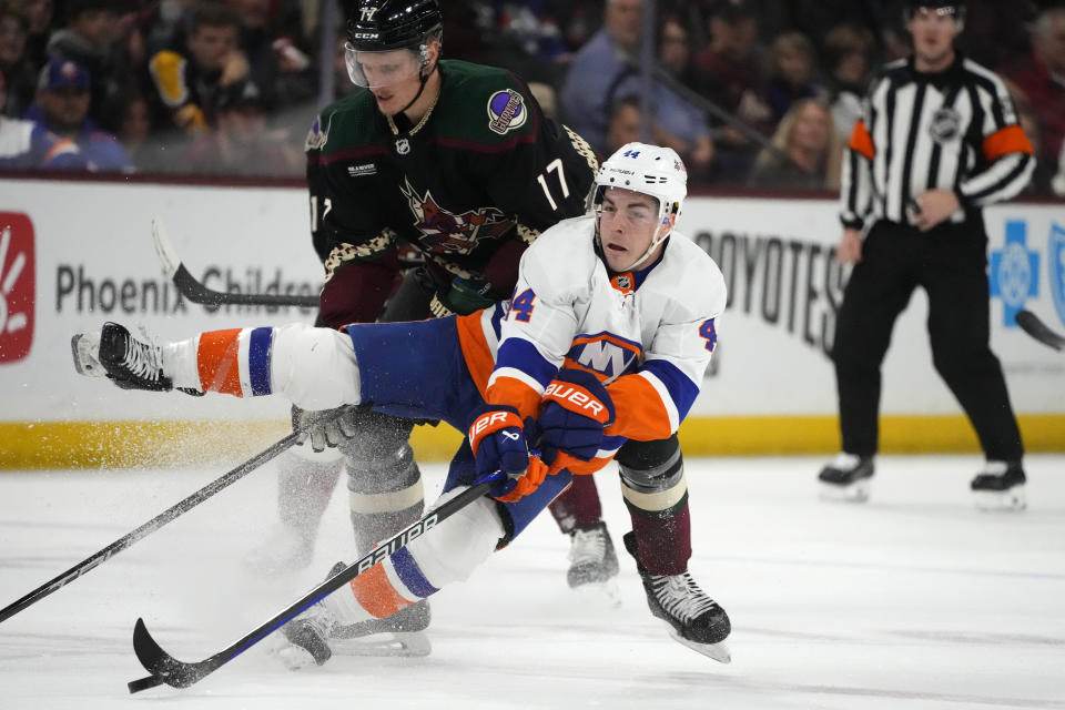 New York Islanders center Jean-Gabriel Pageau (44) is tripped by Arizona Coyotes center Nick Bjugstad (17) during the first period of an NHL hockey game Thursday, Jan. 4, 2024, in Tempe, Ariz. (AP Photo/Ross D. Franklin)