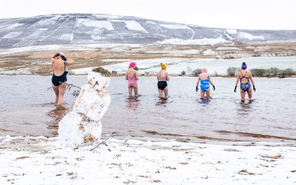 Wild swimmers take to the icy water at Threipmuir Reservoir in the snow covered Pentland Hills near Edinburgh on 29 November 2021 - Katielee Arrowsmith/SWNS