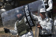 Mexican National Guards brace for the arrival of Central American migrants who crossed the Suchiate River from Guatemala to Mexico near Ciudad Hidalgo, Mexico, Monday, Jan. 20, 2020, as a member of the press works next to them. More than a thousand Central American migrants hoping to reach United States marooned in Guatemala are walking en masse across a river leading to Mexico in an attempt to convince authorities there to allow them passage through the country. (AP Photo/Marco Ugarte)