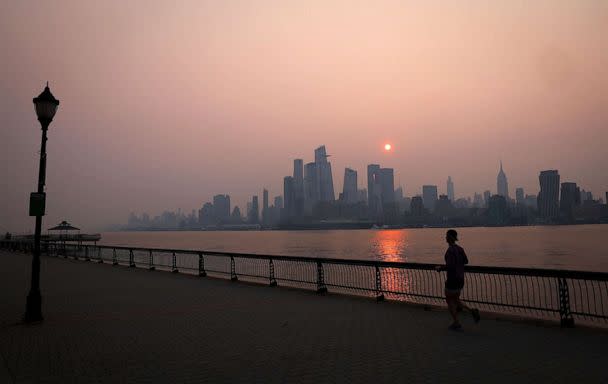 PHOTO: A man jogs along the Hudson River shortly after sunrise, as haze and smoke caused by wildfires in Canada hang over the Manhattan skyline, in New York City, New York, June 7, 2023. (Mike Segar/Reuters)