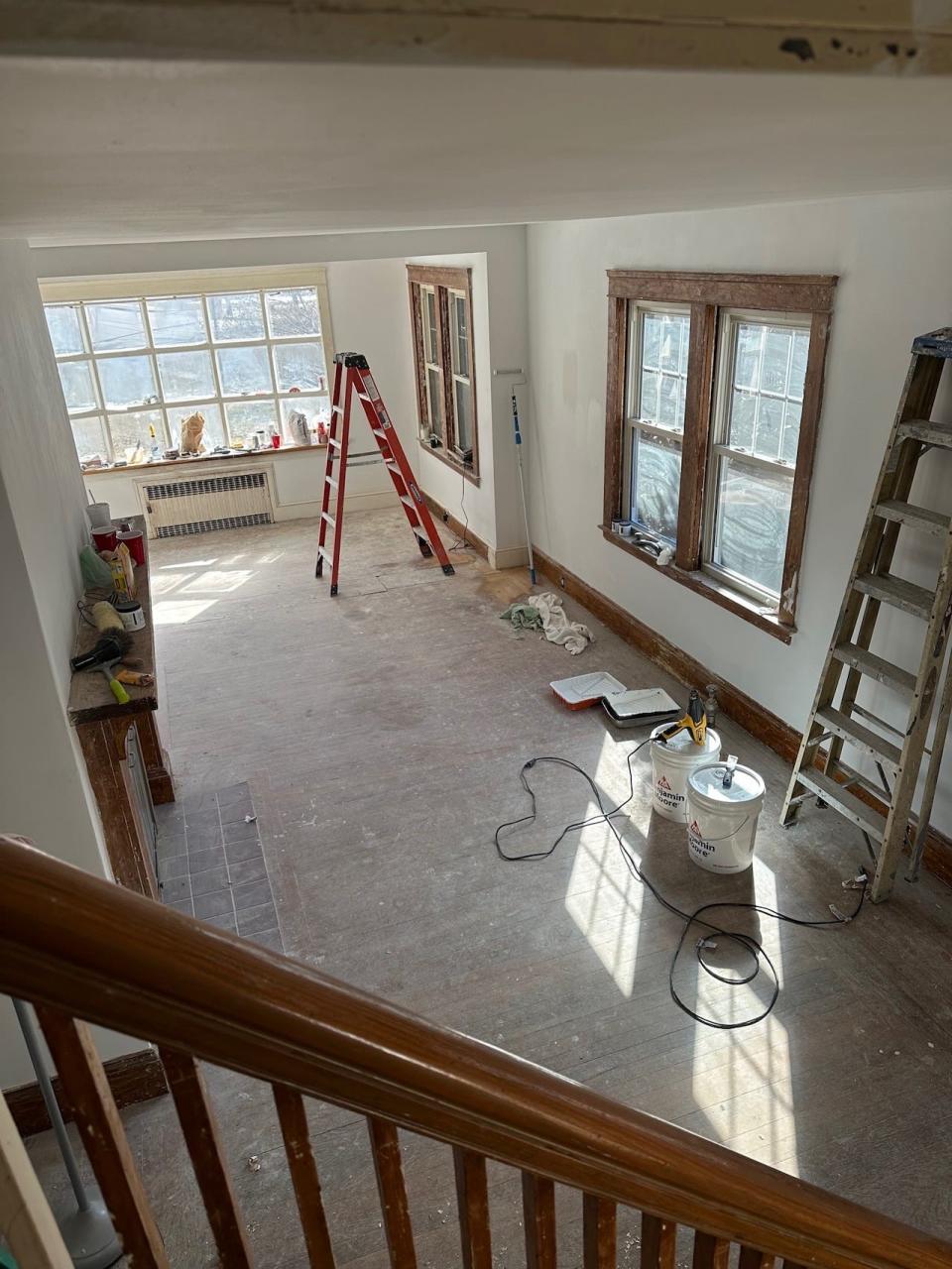 A view of a room in a cottage under renovation with ladders and construction materials.
