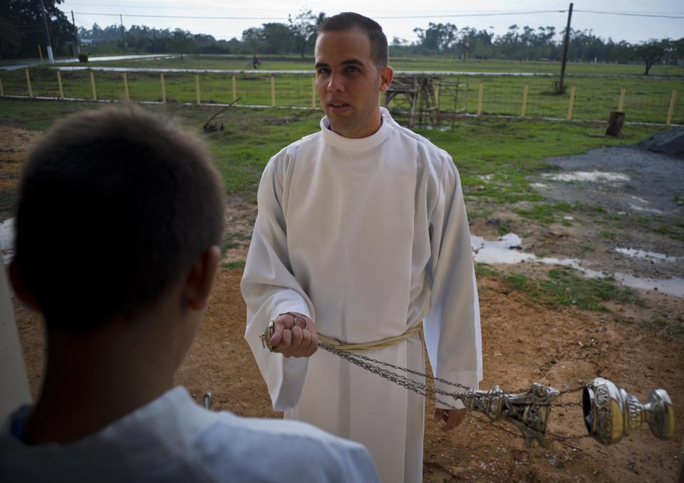 An acolyte, holding a censer, and an altar boy wait for the start of the consecration of the Sagrado Corazon de Jesus Catholic church or Sacred Heart, in Sandino, Cuba, Saturday, Jan. 26, 2019. Of the three Catholic churches the Cuban government has authorized, it's the first one in 60 years to be built and completed. It was finished with the help of Tampa's St. Lawrence Catholic Church in Florida. (AP Photo/Ramon Espinosa)