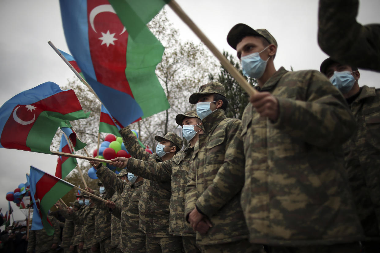 Azerbaijani soldiers hold national flags as they celebrate the transfer of the Lachin region to Azerbaijan's control, as part of a peace deal that required Armenian forces to cede the Azerbaijani territories they held outside Nagorno-Karabakh, in Aghjabadi, Azerbaijan, Tuesday, Dec. 1, 2020. Azerbaijan has completed the return of territory ceded by Armenia under a Russia-brokered peace deal that ended six weeks of fierce fighting over Nagorno-Karabakh. Azerbaijani President Ilham Aliyev hailed the restoration of control over the Lachin region and other territories as a historic achievement. (AP Photo/Emrah Gurel