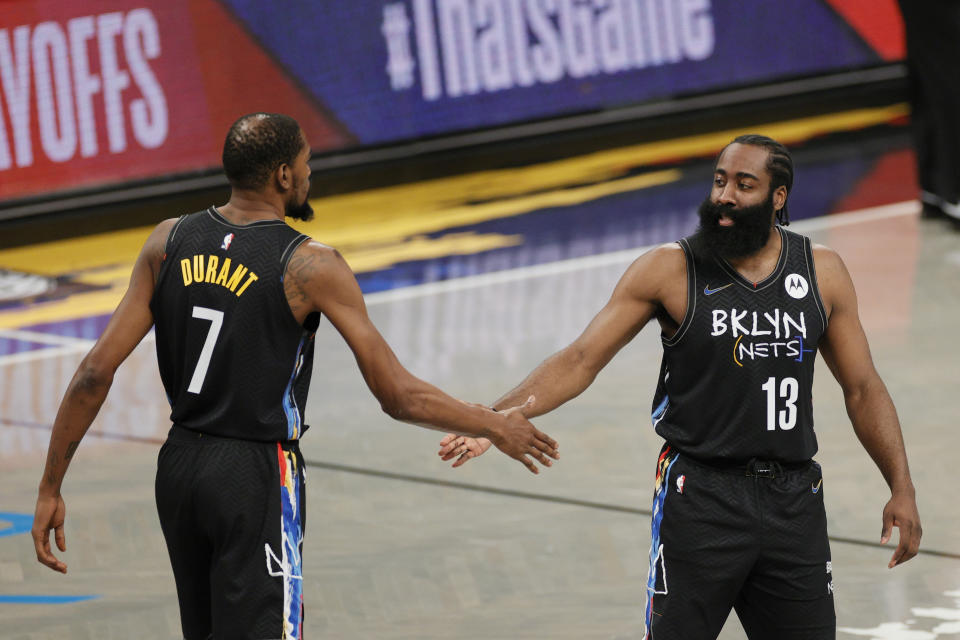 Kevin Durant high-fives James Harden of the Brooklyn Nets.