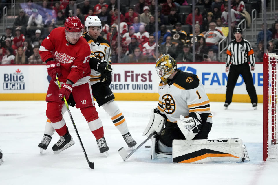 Boston Bruins goaltender Jeremy Swayman (1) stops a Detroit Red Wings left wing Adam Erne (73) shot as Charlie McAvoy (73) defends in the first period of an NHL hockey game Sunday, March 12, 2023, in Detroit. (AP Photo/Paul Sancya)