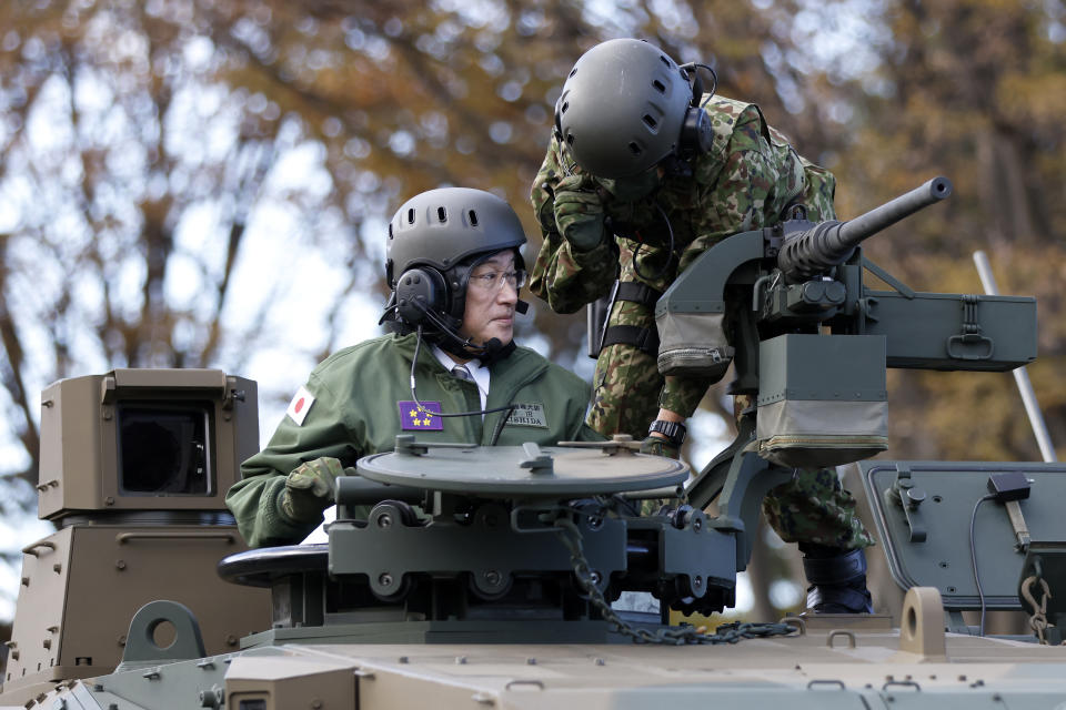 Japan's Prime Minister Fumio Kishida, left, rides on a Japan Ground Self-Defense Force (JGSDF) Type 10 tank during a review at the JGSDF Camp Asaka in Tokyo, Japan, Saturday, Nov. 27, 2021. (Kiyoshi Ota/Pool Photo via AP)
