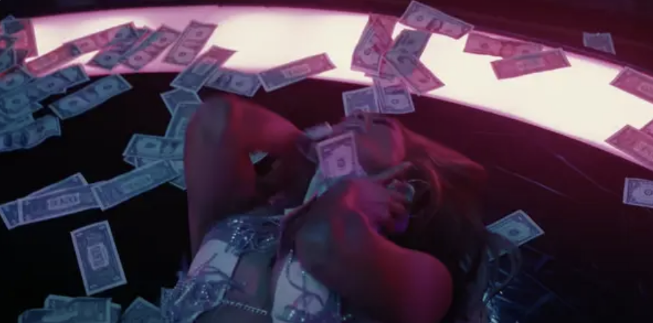 Jennifer Lopez lying on a pile of money in "Hustlers"