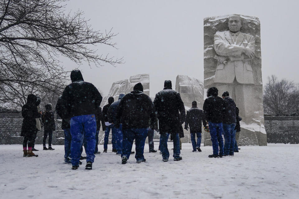 Visitors gather at the Martin Luther King Jr. Memorial as snow falls in Washington, D.C. (AP Photo/Carolyn Kaster)