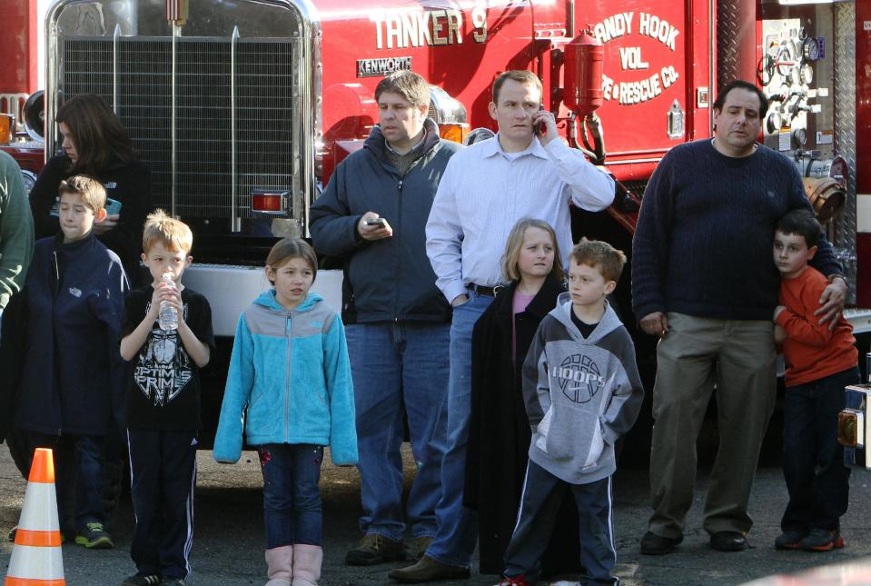 School children wait for their parents at the Sandy Hook firehouse following a mass shooting at the Sandy Hook Elementary School in Newtown, Conn. on Friday, Dec. 14, 2012. (AP Photo/The Journal News, Frank Becerra Jr.) NYC OUT, NO SALES, TV OUT, NEWSDAY OUT; MAGS OUT; MANDATORY CREDIT: THE JOURNAL NEWS, FRANK BECERRA JR.