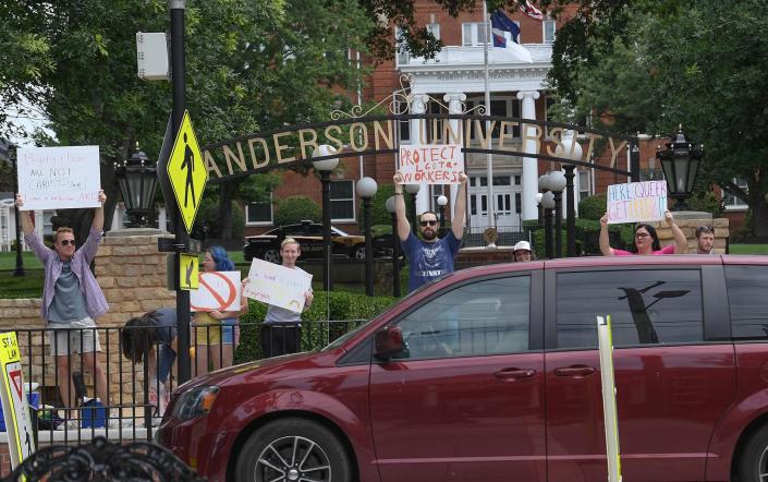 People in support of former professor Miranda Barnett wave signs near passing traffic in front of the arches of Anderson University on Boulevard in Anderson Sunday, June 26, 2022.