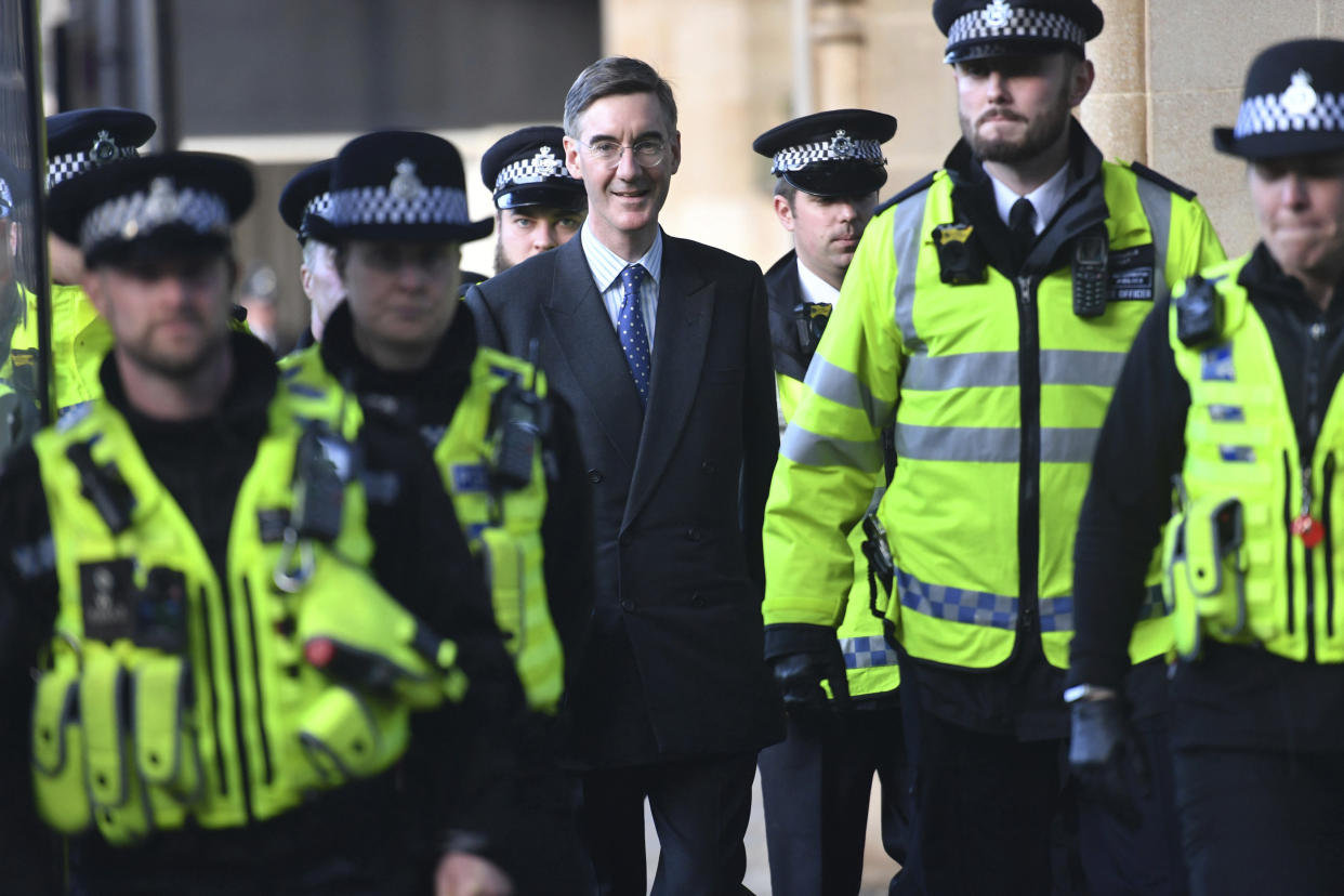 A heavy police presence escorts Leader of Britain's House of Commons Jacob Rees-Mogg from parliament in London, following a Brexit debate Saturday Oct. 19, 2019.  Many thousands of protesters gathered in London to demonstrate on both sides of the Brexit argument.  (Jacob King/PA via AP)