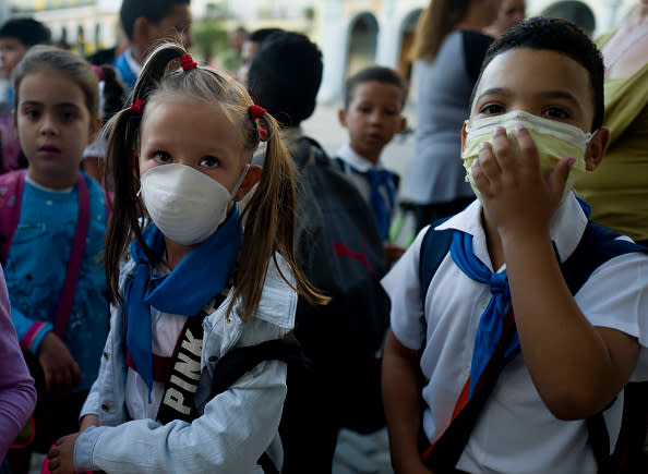 Two children wear a face mask outside of a school in Old Havana, Cuba. Source: Getty