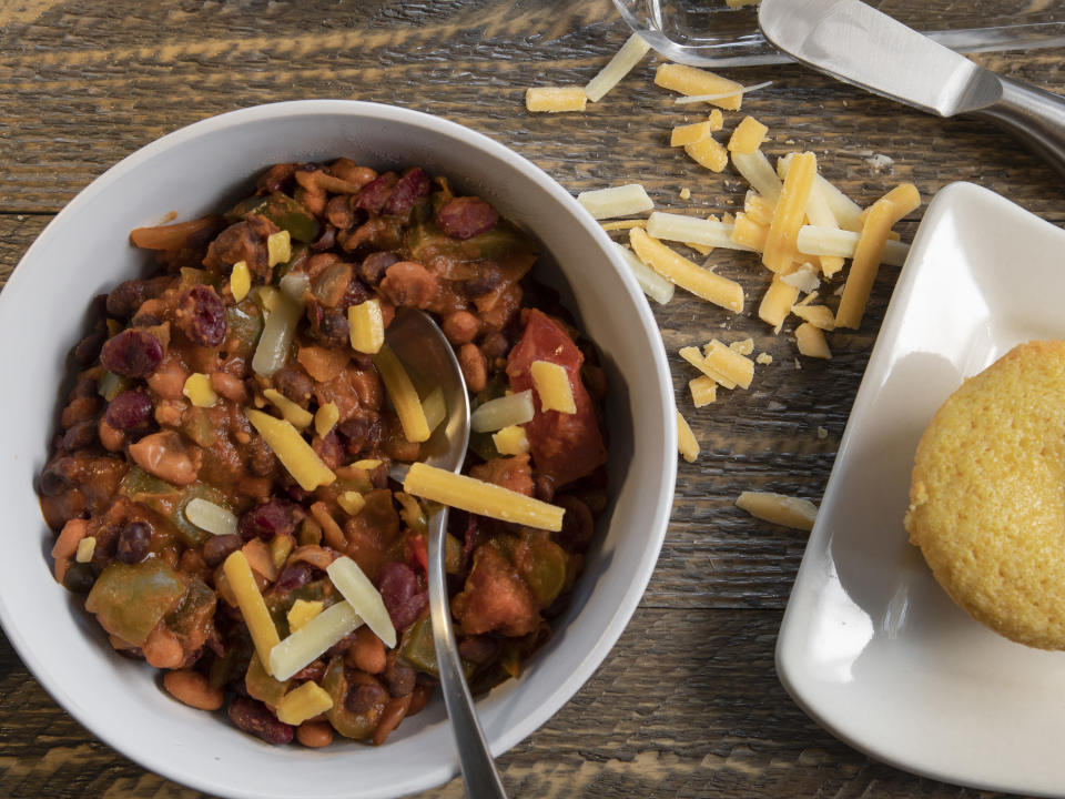 Chili with sprinkles of cheese next to cornbread