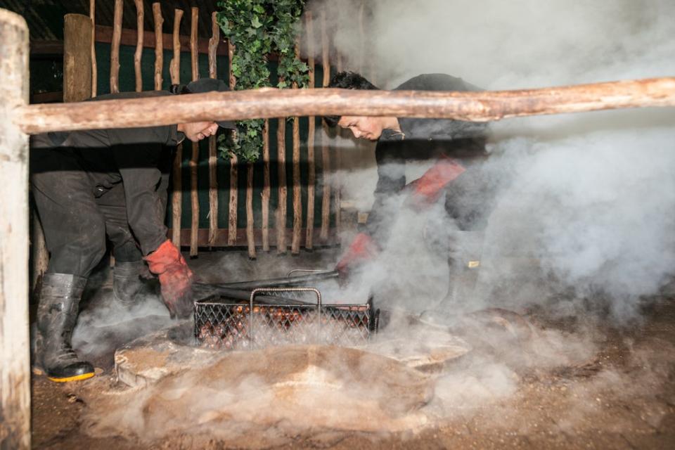 Smoke and dust fly as food is prepared for a traditional Maori feast by hāngi, steaming through heat from underground thermal activity or heated stones in the base of a pit (Getty)