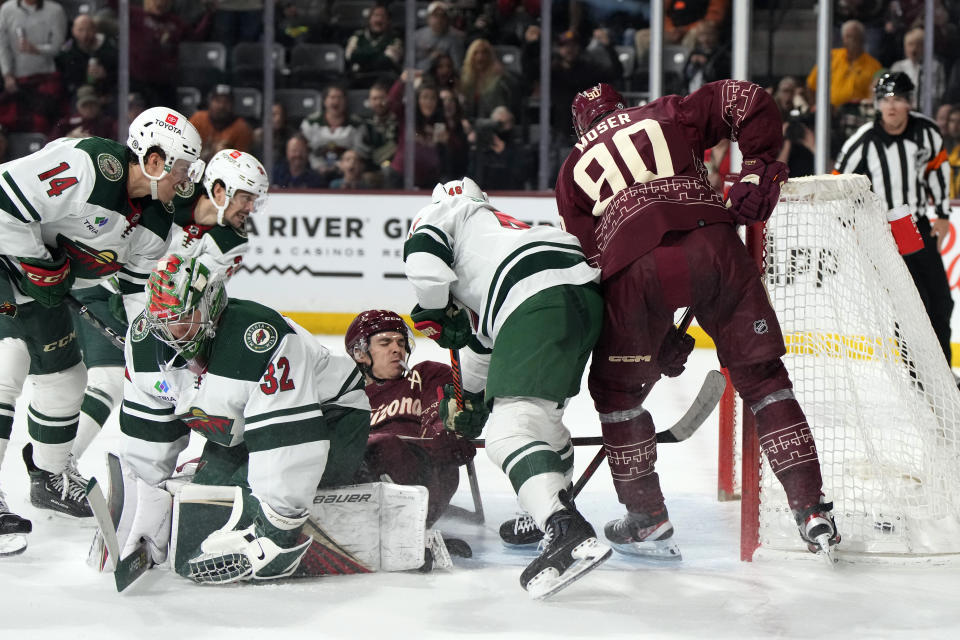 Arizona Coyotes right wing Clayton Keller scores a goal in overtime surrounded by defenseman J.J. Moser (90), Minnesota Wild center Joel Eriksson Ek (14), goaltender Filip Gustavsson (32), and defenseman Jared Spurgeon (46) during an NHL hockey game, Sunday, March 12, 2023, in Tempe, Ariz. Arizona won 5-4 in overtime. (AP Photo/Rick Scuteri)