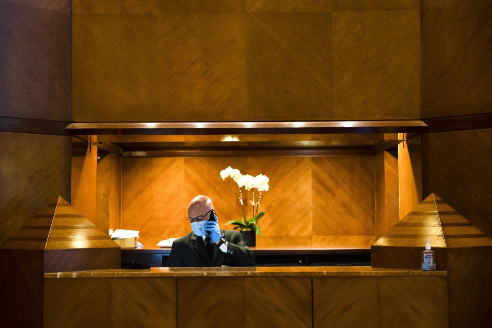 Concierge Joe DeLuca, poses for a photograph at the front desk of an apartment building in New York, April 6, 2020. While tens of thousands of New Yorkers work at home during the COVID-19 pandemic, people like DeLuca keep the city running amid the lockdown. (AP Photo/Matt Rourke)