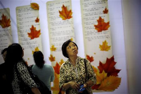 A woman looks at signs showing the personal profiles of people looking for spouses during a matchmaking event for middle-aged singles and seniors, sponsored by Shanghai's government, in Shanghai November 9, 2013. REUTERS/Carlos Barria