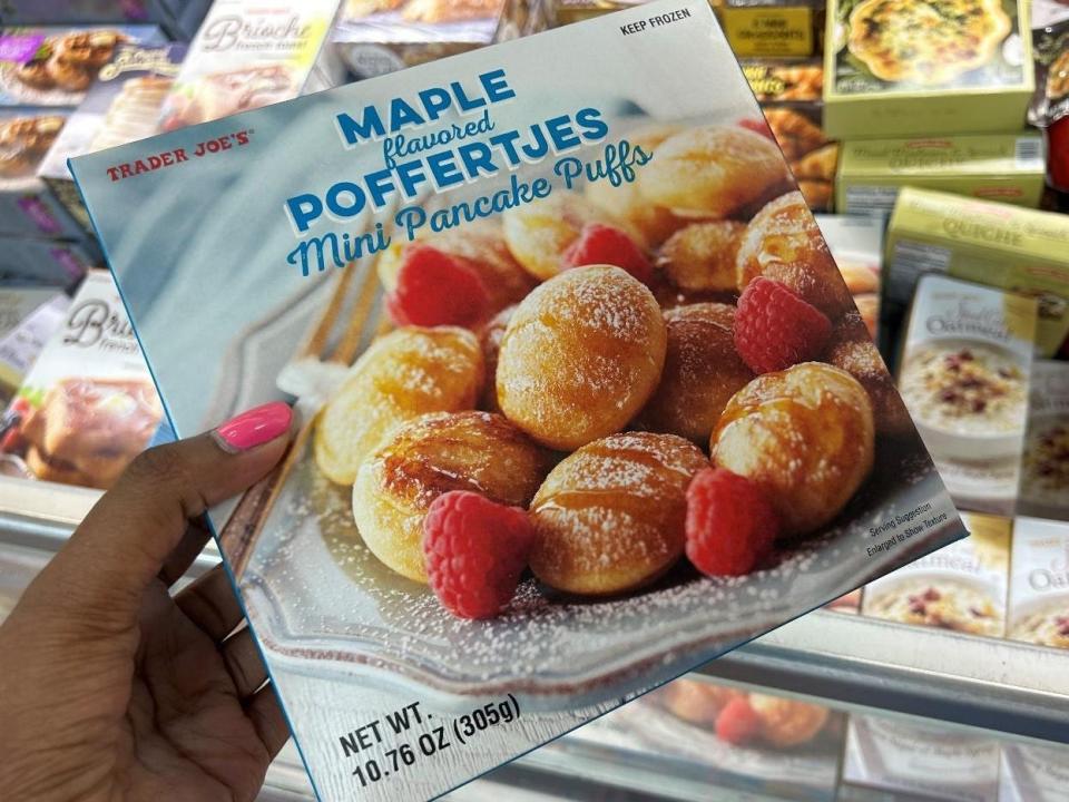 Woman holding box of maple-flavored mini pancake puffs from Trader Joe's.