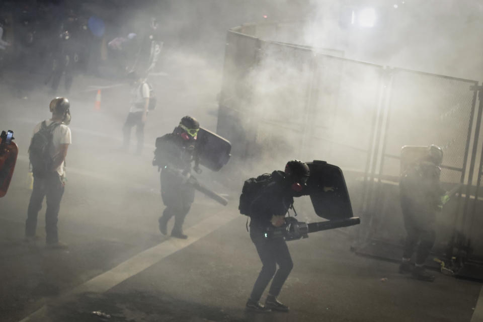 Demonstrators use leaf blowers to try to blow back tear gas launched by federal officers during a Black Lives Matter protest at the Mark O. Hatfield United States Courthouse Sunday, July 26, 2020, in Portland, Ore. (AP Photo/Marcio Jose Sanchez)