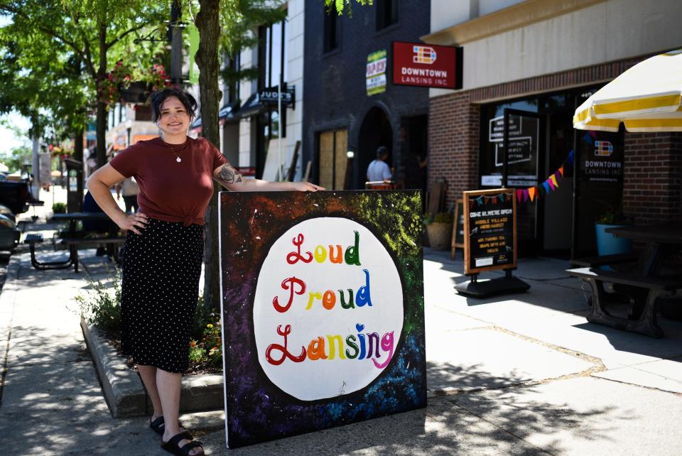 Former Lansing Promise scholarship recipient Kylee Kellett of Lansing pictured Thursday, June 16, 2022, outside of Downtown Lansing Inc.'s Middle Village Micro Market with her latest painting "Loud Proud Lansing." She created the painting live June 2 during the Block Aid Street Festival at the intersection of Washtenaw and South Washington Square.