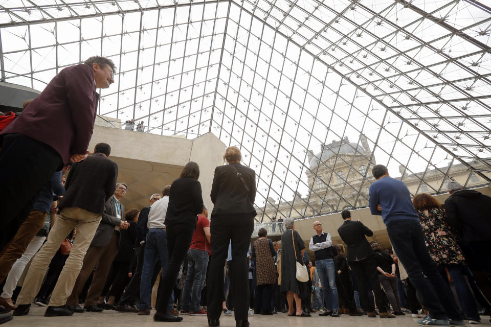 Le Louvre museum employees and tourists gather under the giant glass pyramid by late architect I.M. Pei, Friday, May 17, 2019 in Paris. Pei died earlier this week at the age of 102. (AP Photo/Michel Euler)