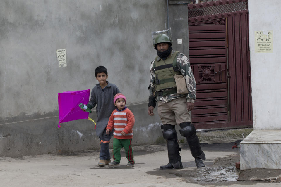Kashmiri children walk past an Indian paramilitary soldier during a security lockdown in downtown Srinagar, Indian controlled Kashmir, Friday, March 1, 2019. India has banned Jama'at-e-Islami, a political-religious group in Kashmir, in a sweeping and ongoing crackdown against activists seeking the end of Indian rule in the disputed region amid the most serious confrontation between India and Pakistan in two decades. (AP Photo/ Dar Yasin)