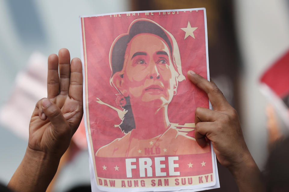 FILE - Myanmar nationals living in Thailand hold pictures of Myanmar leader Aung San Suu Kyi gesture with a three-fingers salute, a symbol of resistance, as they protest in front of the Myanmar Embassy in Bangkok, Thailand on Feb. 8, 2021. The four-year prison sentence given to ousted Myanmar leader Suu Kyi on Monday, Dec. 6, 2021 on charges of incitement and failing to observe pandemic restrictions is one small shot in a legal offensive intended to deal her and her National League for Democracy party a crippling political blow. (AP Photo/Sakchai Lalit, File)