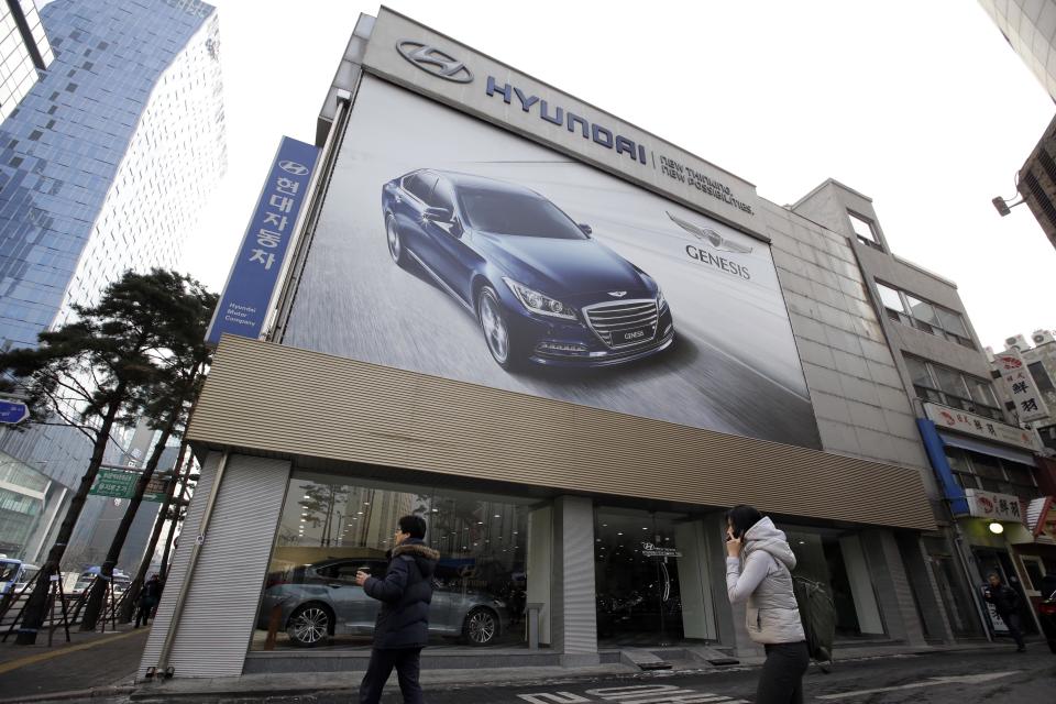 People walk by a Hyundai Motor Co. showroom in Seoul, South Korea, Thursday, Jan. 23, 2014. Hyundai Motor Co. said its fourth-quarter profit increased 13 percent over a year earlier thanks to higher overseas sales. (AP Photo/Lee Jin-man)