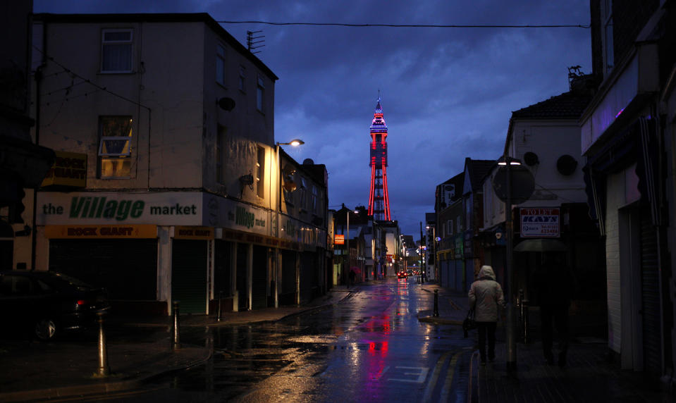 A woman walks down a side road towards the Tower in Blackpool, northern England September 8, 2013. British beach resorts, which flourished in the 19th century and earlier, have tempted tourists for years with amusement arcades, fairground rides and cheap and cheerful souvenirs. However, as a 2013 report by the Centre for Social Justice states, many seaside towns suffered as from the 1970s it became cheaper and easier for British tourists to travel abroad. Now, according to the Office for National Statistics, larger seaside towns in England suffer from higher-than-average levels of deprivation compared to the rest of the country. Nevertheless, they do continue to attract holiday makers. Picture taken September 8, 2013.  REUTERS/Phil Noble (BRITAIN - Tags: SOCIETY TRAVEL)