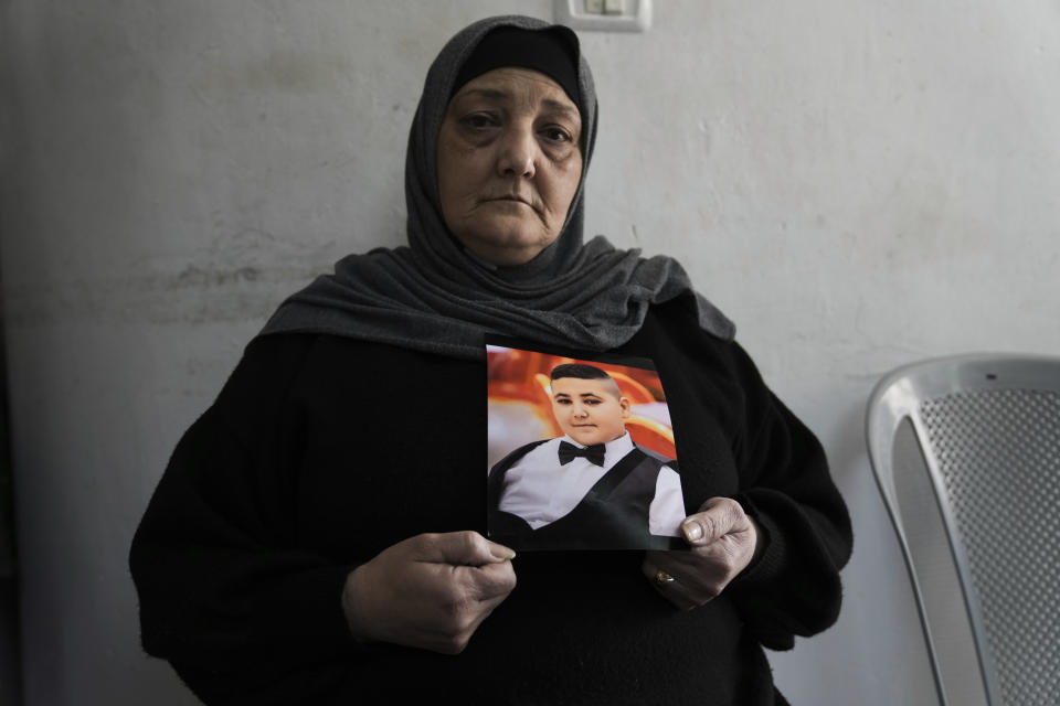 Rawiya Halhouli sostiene una foto de su hijo asesinado Rami Halhouli en la vivienda familiar en el campo de refugiados de Shuafat, en Jerusalén Oriental, el domingo 17 de marzo de 2024. Halhouli, de 12 años, murió baleado por un policía israelí cuando lanzaba fuegos artificiales el 12 de marzo. (AP Foto/Mahmoud Illean)