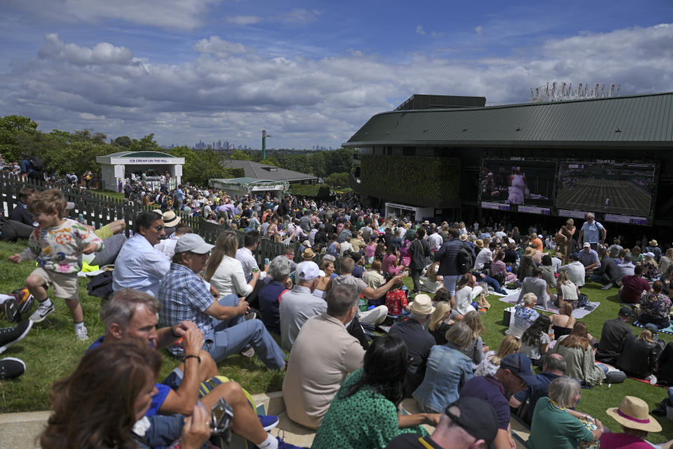 Crowds flock on the Hill outside court one on day two of the Wimbledon tennis championships in London, Tuesday, June 28, 2022. Many places, particularly those that have loosened safety requirements, are seeing what passes for a go-go summer of sunny optimism and adventure. (AP Photo/Alberto Pezzali)