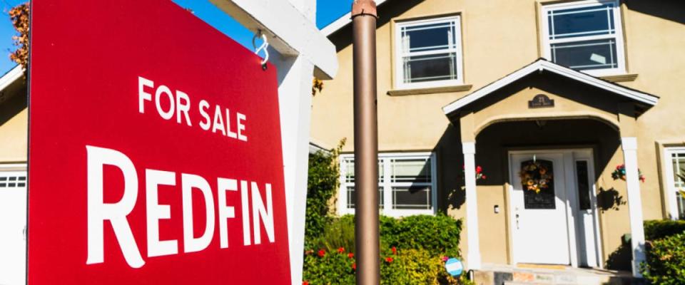 A house with a for sale sign from real estate company Redfin in front