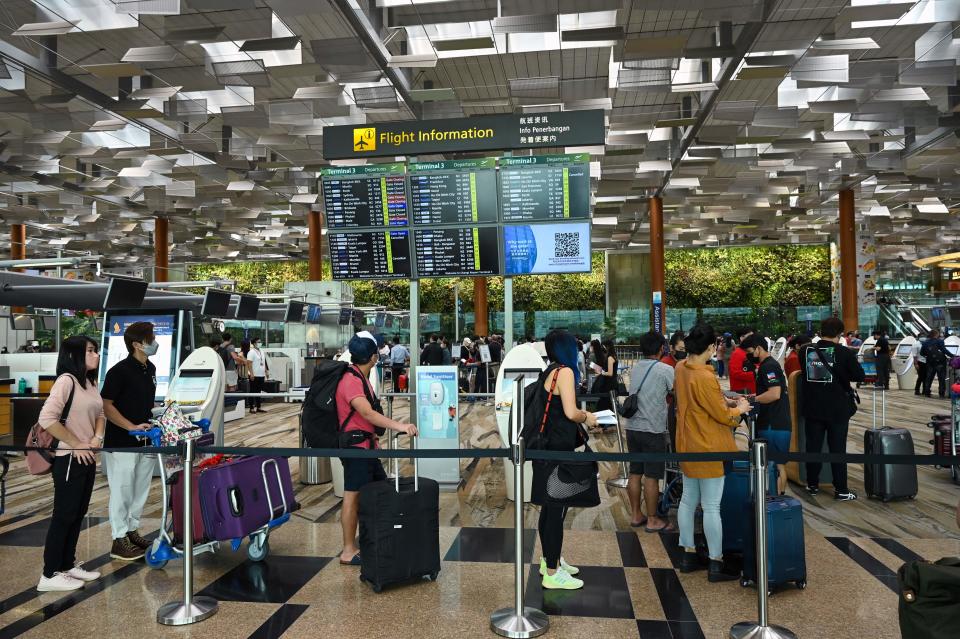 Travellers queue for self check-in before departure at Changi International Airport in Singapore on April 1, 2022, as Singapore reopened its land and air borders to travellers fully vaccinated against the Covid-19 coronavirus. (Photo by Roslan RAHMAN / AFP) (Photo by ROSLAN RAHMAN/AFP via Getty Images)