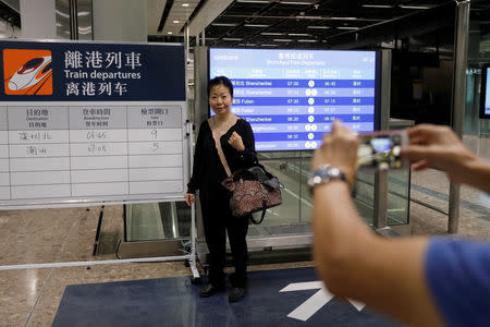 A passenger poses with train schedules during the first day of service of the Hong Kong Section of the Guangzhou-Shenzhen-Hong Kong Express Rail Link, in Hong Kong, China September 23, 2018. REUTERS/Tyrone Siu