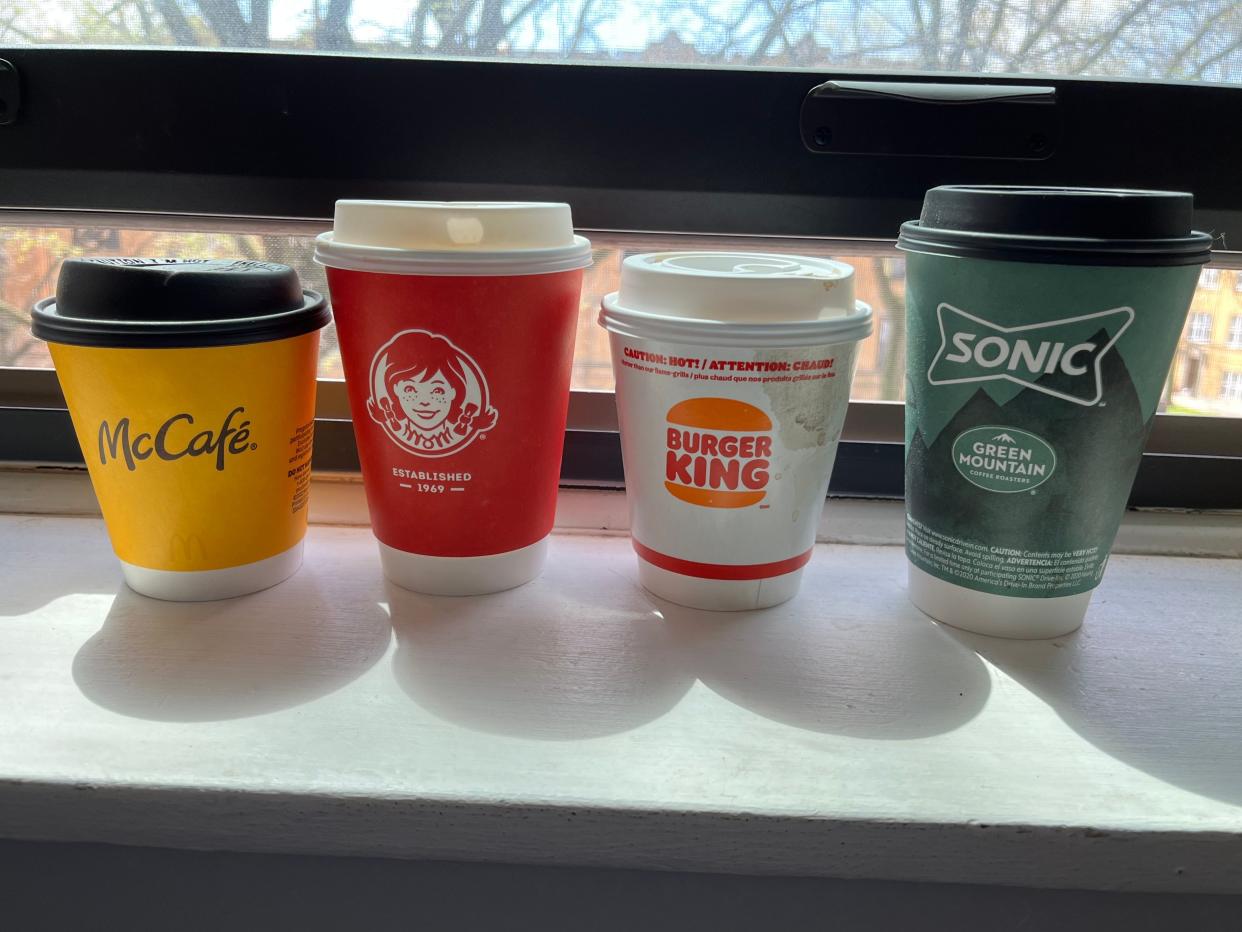 small coffee cups from mccafe, wendy's, burger king, and sonic sitting on a window ledge