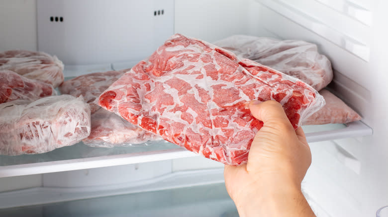 hand grabbing frozen meat