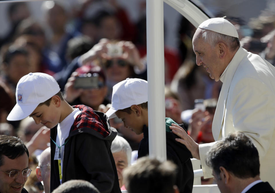 Pope Francis greets 11-year-olds Livio Bastianelli, right, and Davide Maria Bianchi after inviting them on the pope-mobile during his weekly general audience in St. Peter's Square, at the Vatican, Wednesday, April 16, 2014. Pope Francis has given a lift to two lucky kids during his general audience in St. Peter's Square. A particularly jovial Francis hopped off his white, open-air car Wednesday to greet a group of fifth graders from Perugia who presented him with a T-shirt from their school. Seemingly joking, Francis asked if any of them wanted to take a spin through the square. "Me! Me! Me!" they yelled. Francis picked 11-year-olds Livio Bastianelli and Davide Maria Bianchi and the two hopped aboard. (AP Photo/Gregorio Borgia)