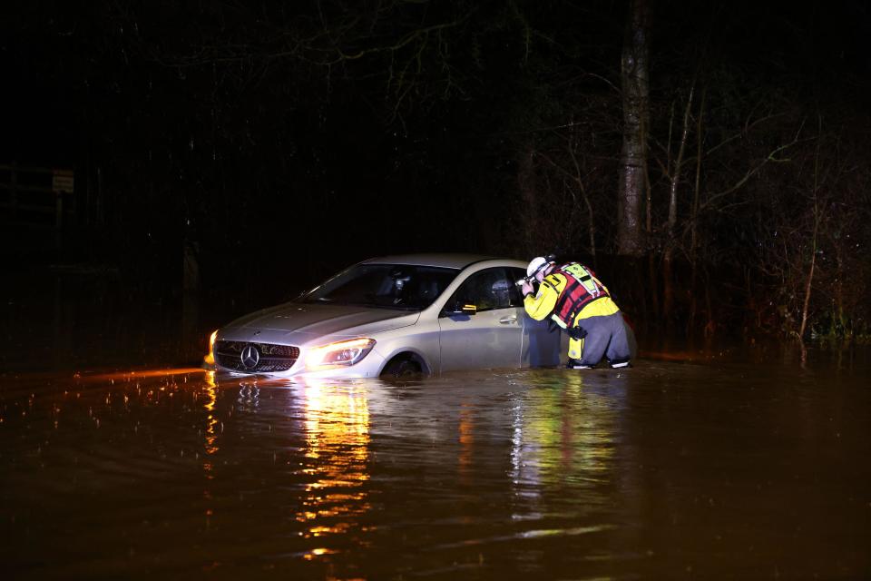 Hathern, Leicestershire, UK. 2nd January 2024. UK weather. A Fire Fighter checks inside a car stranded in flood water. High winds and heavy rain are battering a large swathe of the UK as the small but potent Storm Henk hits.  Credit Darren Staples/Alamy Live News.