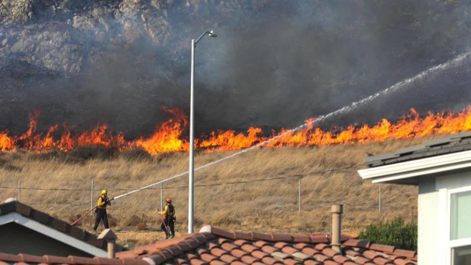 Firefighters battle a brush fire that burned about 50 acres and threatened homes along the South Street Hills in San Luis Obispo on Sept. 6, 2020.