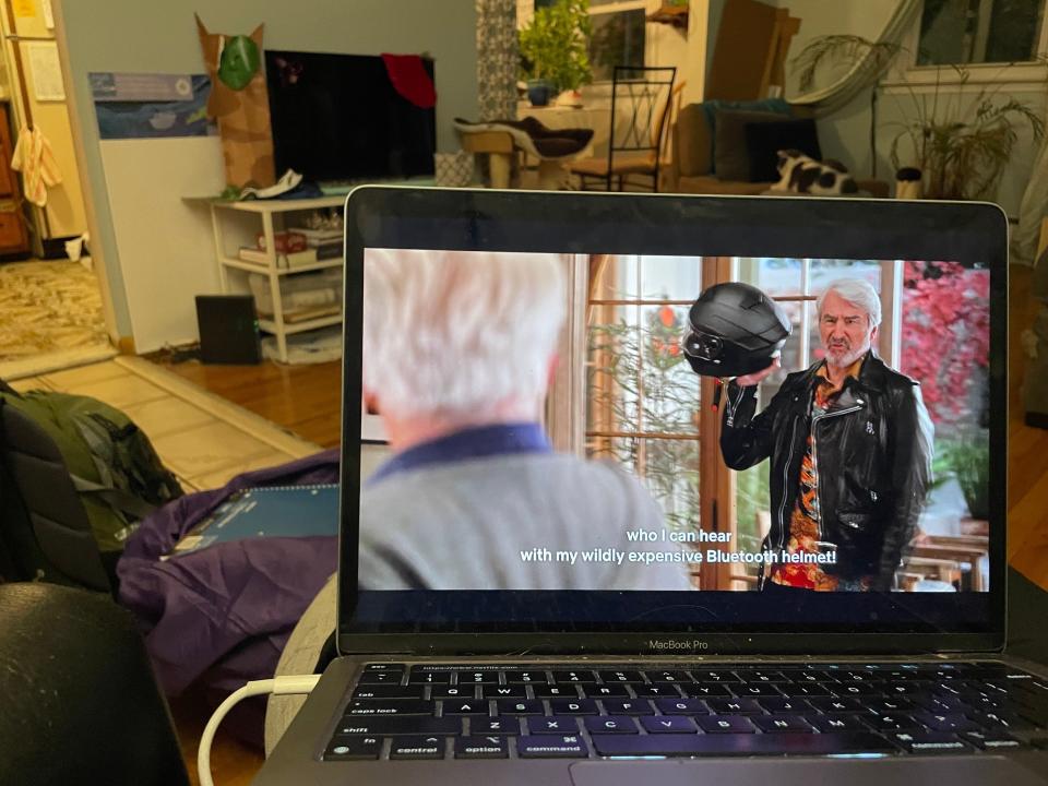 A laptop with a show on it and a living room.