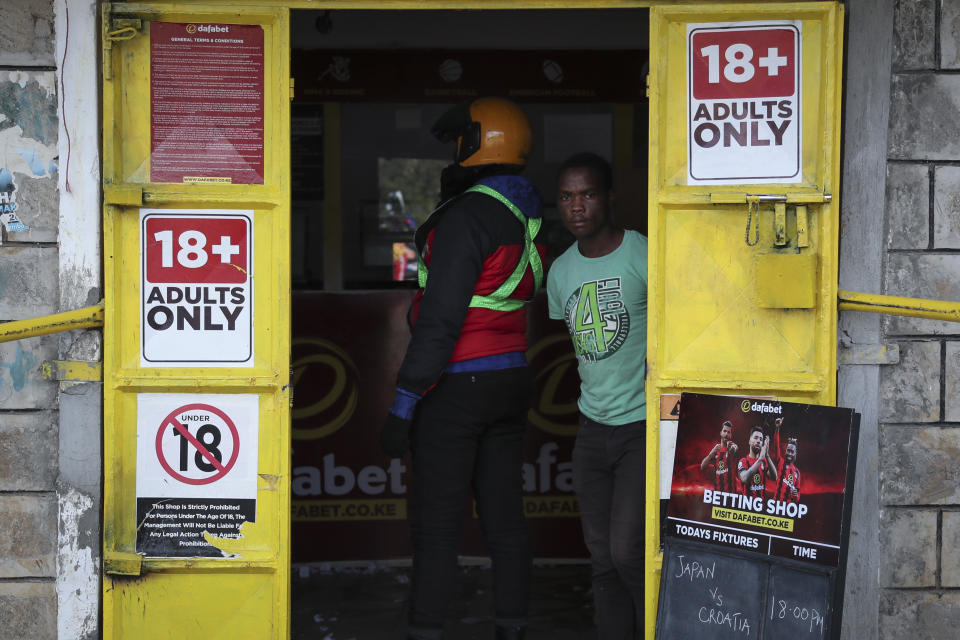 A man looks out of a sports betting shop in the low-income Kibera neighborhood of the capital Nairobi, Kenya, Monday, Dec. 5, 2022. Although sports betting is a global phenomenon and a legitimate business in many countries, the stakes are high on the continent of 1.3 billion people because of lax or non-existent regulation, poverty and widespread unemployment. (AP Photo/Brian Inganga)